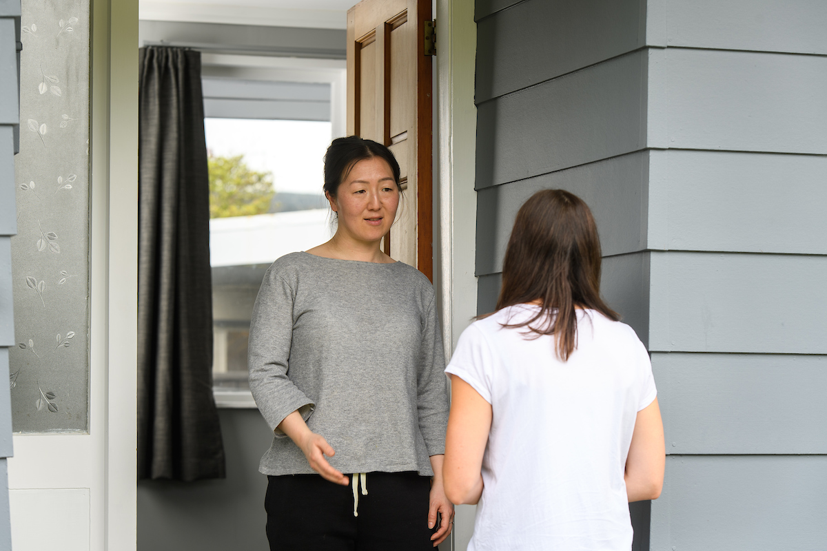 Two women at a doorstep, symbolising a friend offering support to someone in need